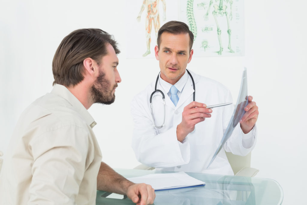 Male doctor explaining spine x-ray to patient in the medical office